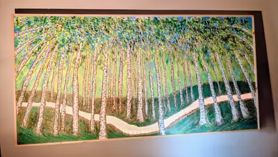 A framed carved panel of an aspen grove in greens and golds, the trunks cut in relief.