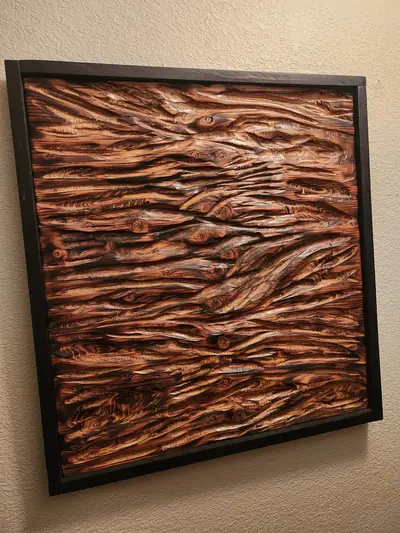 A framed wall panel carved into deep flowing timber texture and finished in warm copper tones.