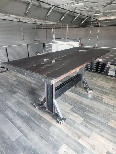 A long dark epoxy conference table on a polished steel base, photographed in the shop before delivery.