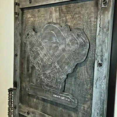 Grey stained wood door panel with a V8 engine cutaway engraved in fine white line work, framed by bolted timber with fractal burn detail