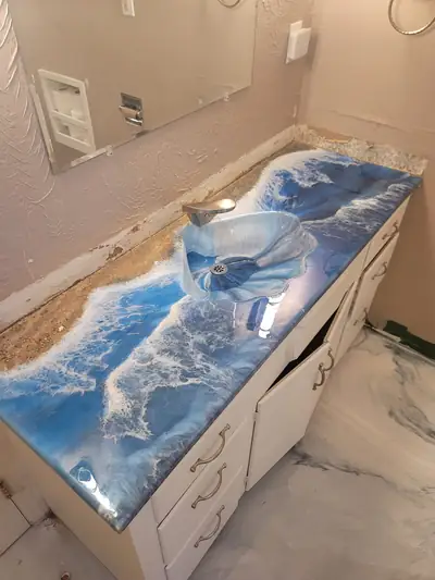 Epoxy bathroom vanity top poured as a blue and white breaking ocean wave with a glass basin
