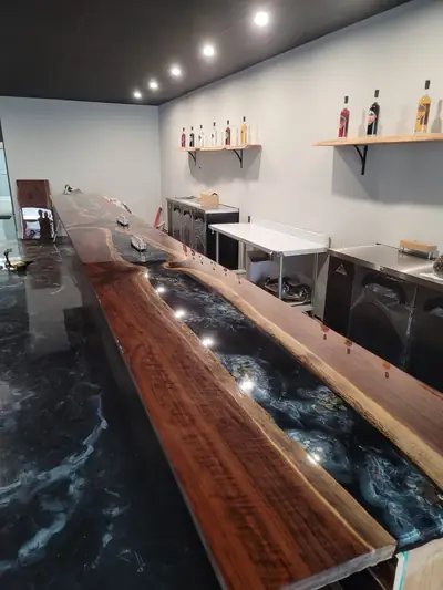 Long live edge walnut bar top with a dark epoxy river running its length in a commercial bar