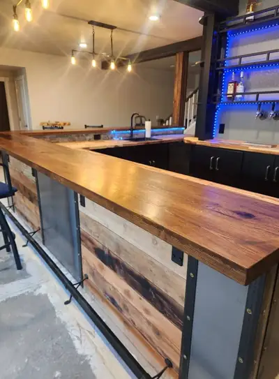 Home bar with a dark epoxy counter and a front clad in mixed reclaimed wood boards