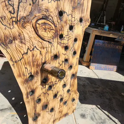 Wall mounted wine rack made from a spalted live edge slab with bottles set into drilled openings