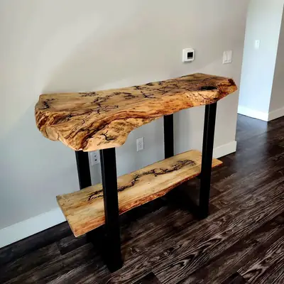 Spalted maple live edge console table on black steel legs with a live edge lower shelf, against a grey wall on a dark wood floor