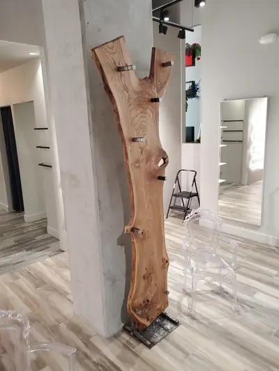 A tall live edge slab standing on end as a floor sculpture, its openings left raw, against a white column.