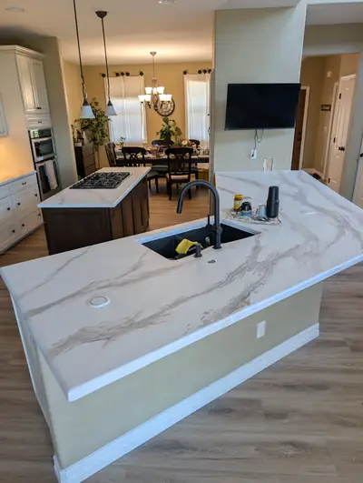 A large kitchen island topped in white marble effect epoxy with soft grey veining, poured and finished on site.